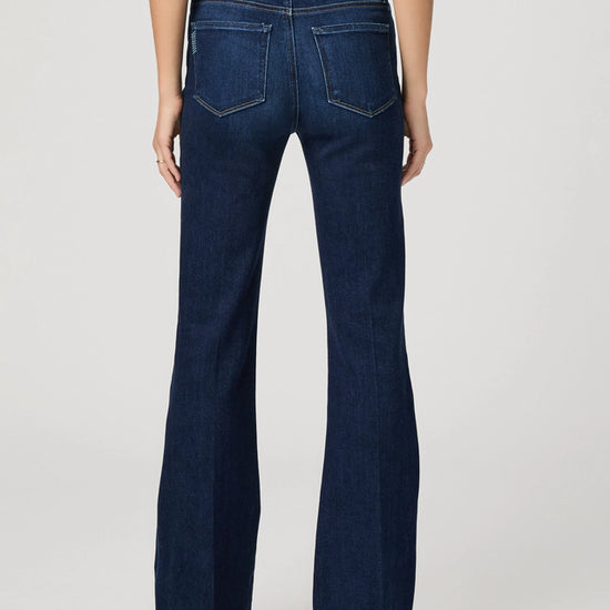 Dark blue flared jeans worn by a person on a light gray background