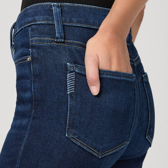 Close-up of blue jeans with a hand in the pocket on a light gray background