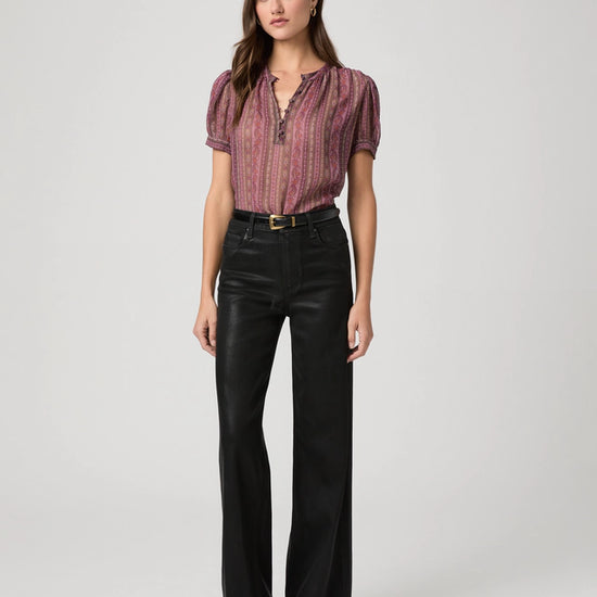 Black waxed look wide leg jeans worn with pink short sleeve blouse