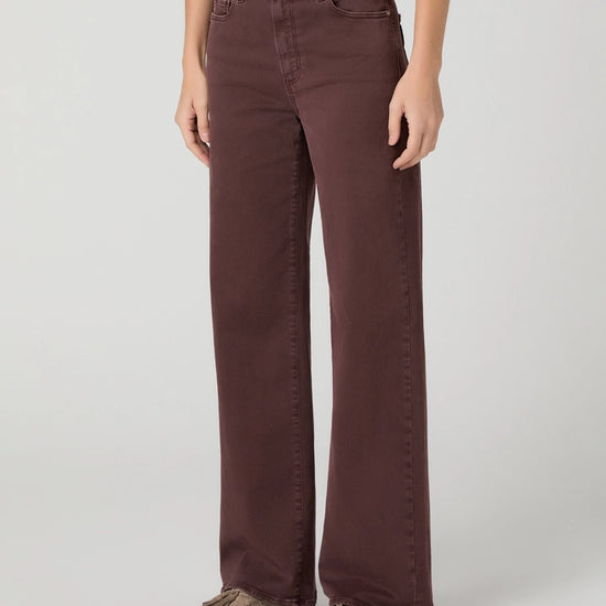 model wearing dark berry coloured jeans and brown shoes on a white background