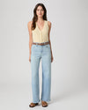 Woman wearing a yellow sleeveless top and light blue jeans on a white background