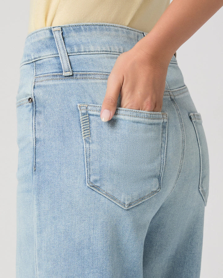 Light blue jeans with a hand in the pocket on a plain background