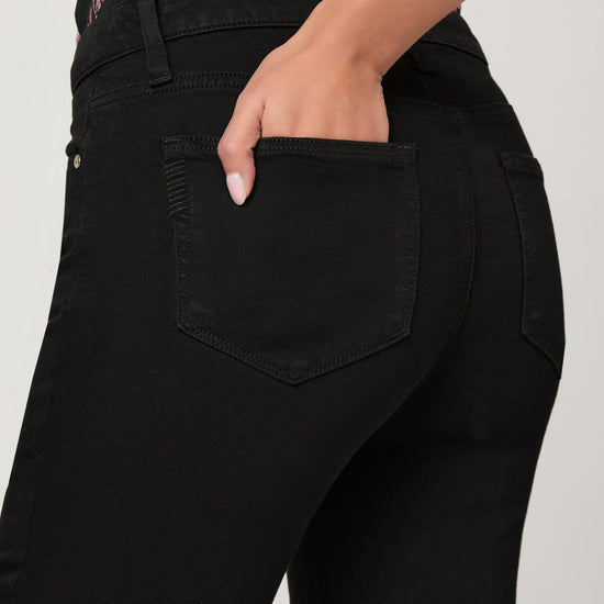 Person wearing black jeans with a floral top, focusing on the pants.