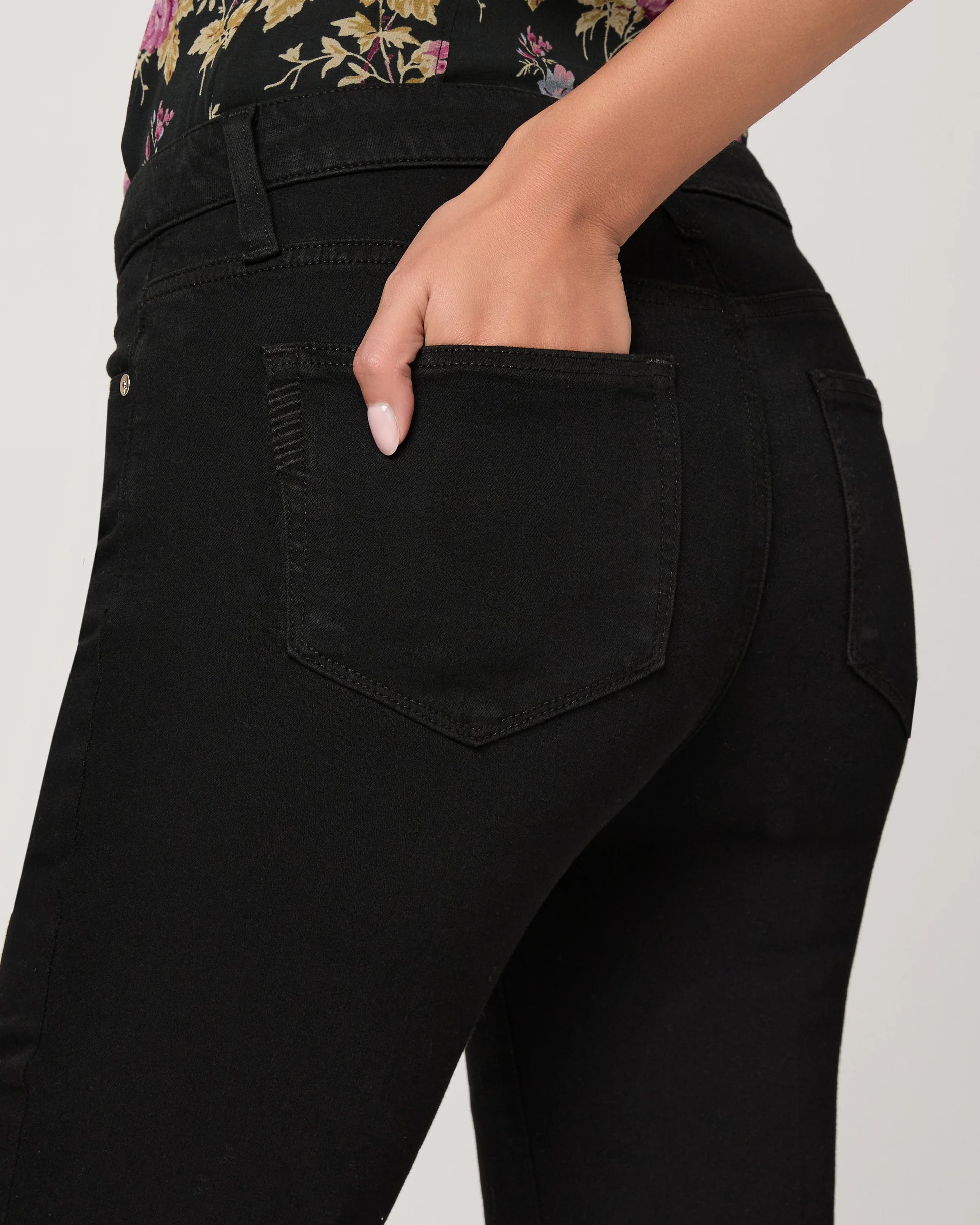 Person wearing black jeans with a floral top, focusing on the pants.