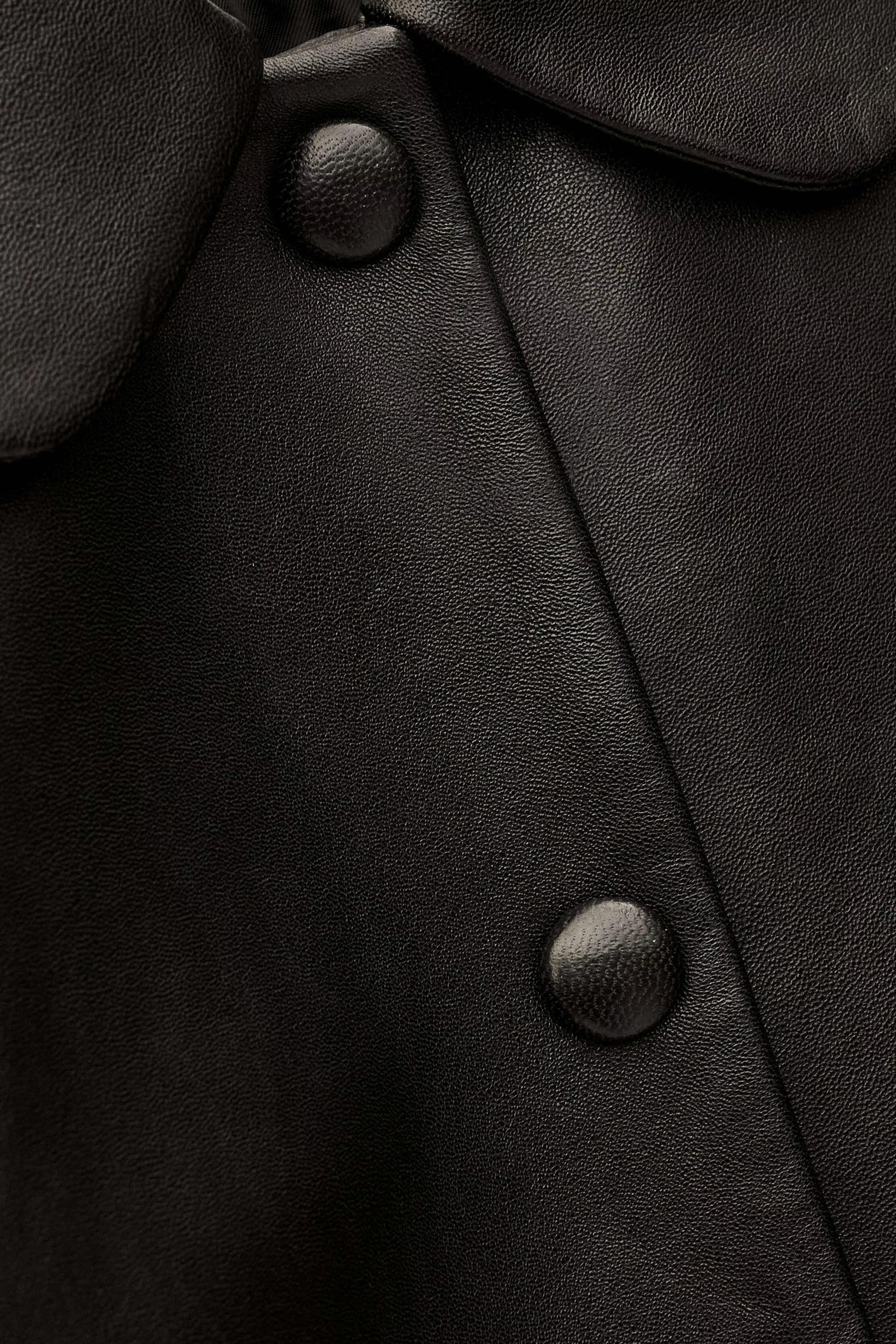 Close-up of a black leather coat with buttons