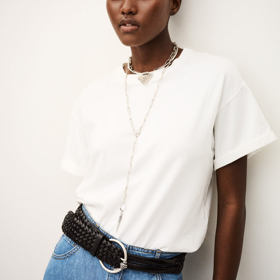Woman wearing a white t-shirt and blue denim skirt with a black belt against a white background from ba&sh