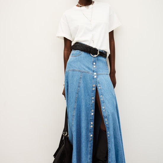 Person wearing a white top, blue denim skirt, and black shoes on a white background from ba&sh