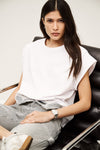 Woman sitting on a black leather chair wearing a white top and striped pants. from ba&sh