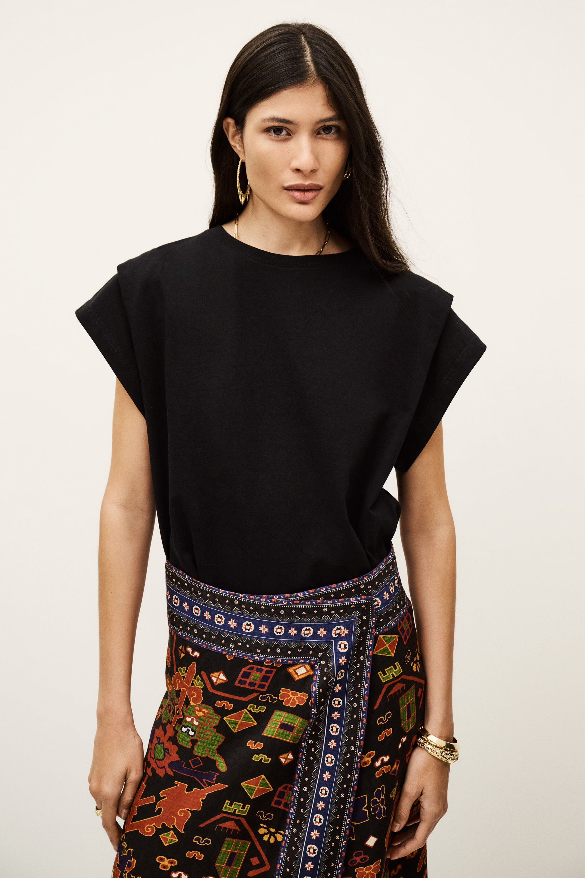 Woman wearing a black top and colorful patterned skirt on a white background from ba&sh