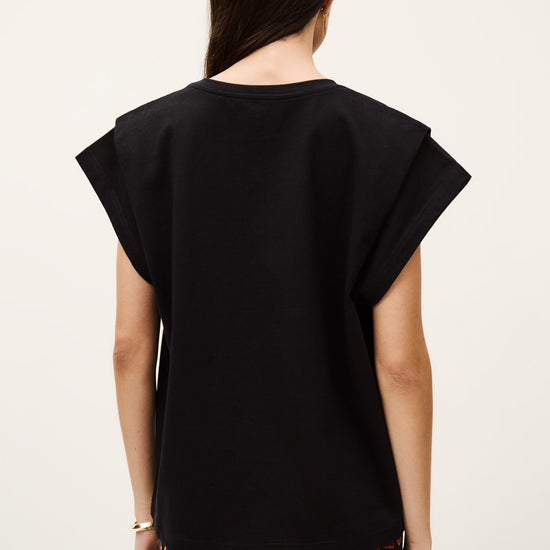 Woman wearing a black top with a plain background from ba&sh