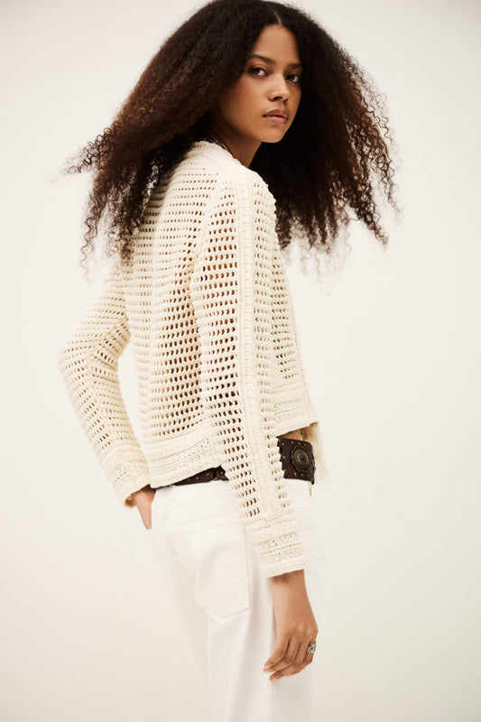 Woman wearing a white textured sweater against a plain background from bash