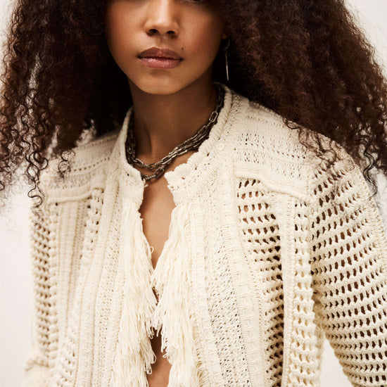 Woman wearing a white knitted cardigan with a neutral background from bash