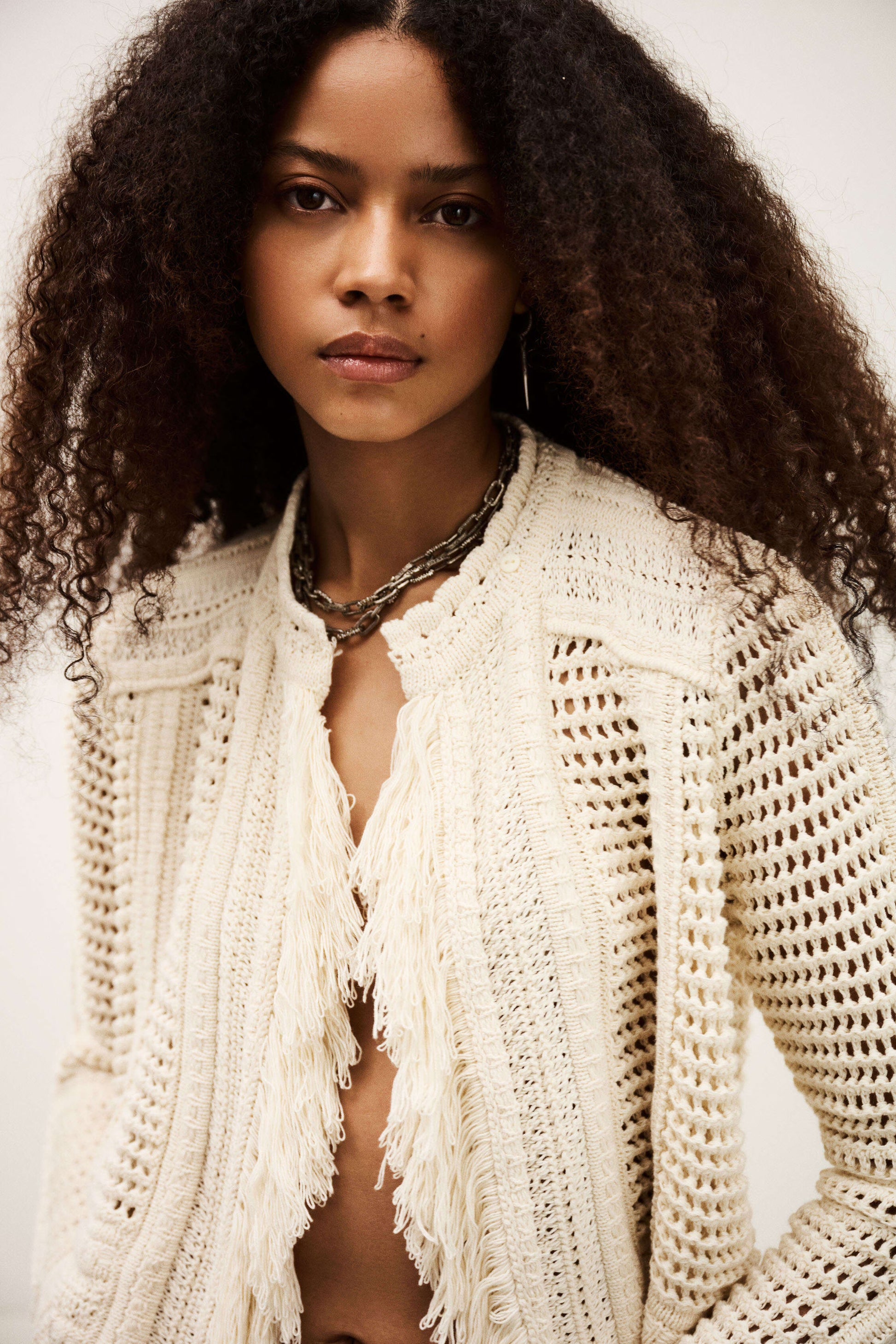 Woman wearing a white knitted cardigan with a neutral background from bash