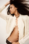 Woman wearing a white knitted cardigan against a neutral background from bash