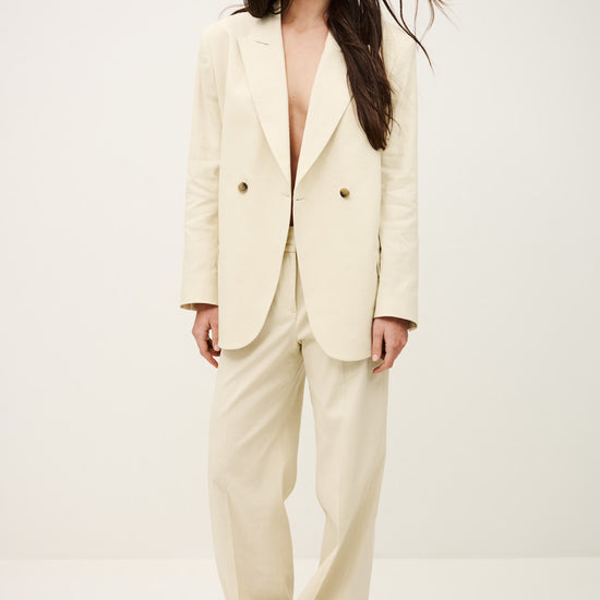 Woman wearing a cream-colored suit against a white background