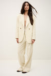 Woman wearing a cream-colored suit against a white background