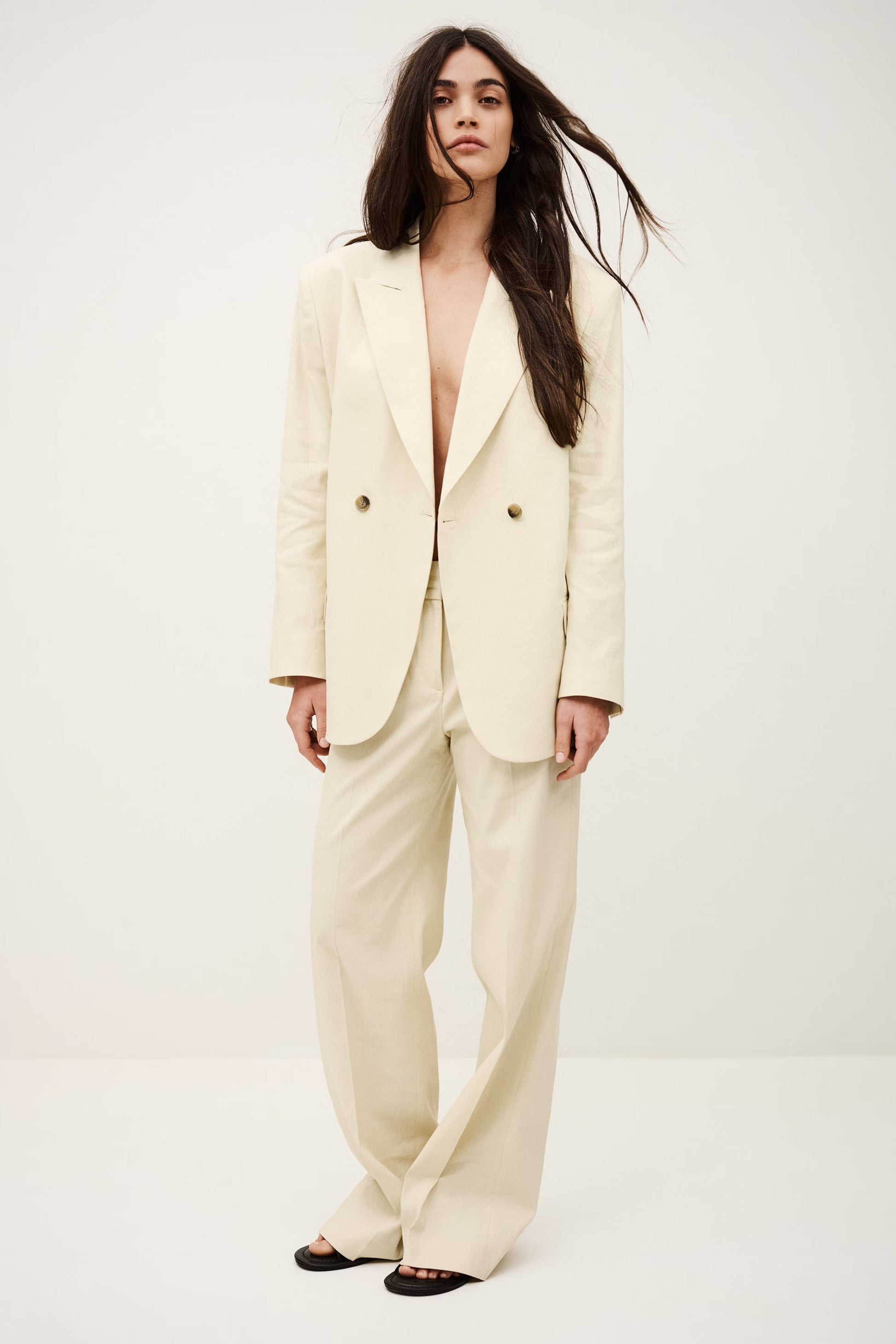 Woman wearing a cream-colored suit against a white background
