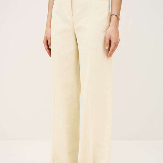 Person wearing cream-colored wide-leg pants on a plain background