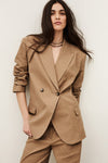 Woman wearing a beige suit against a plain background