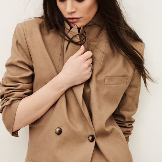 Woman wearing a brown blazer against a plain background