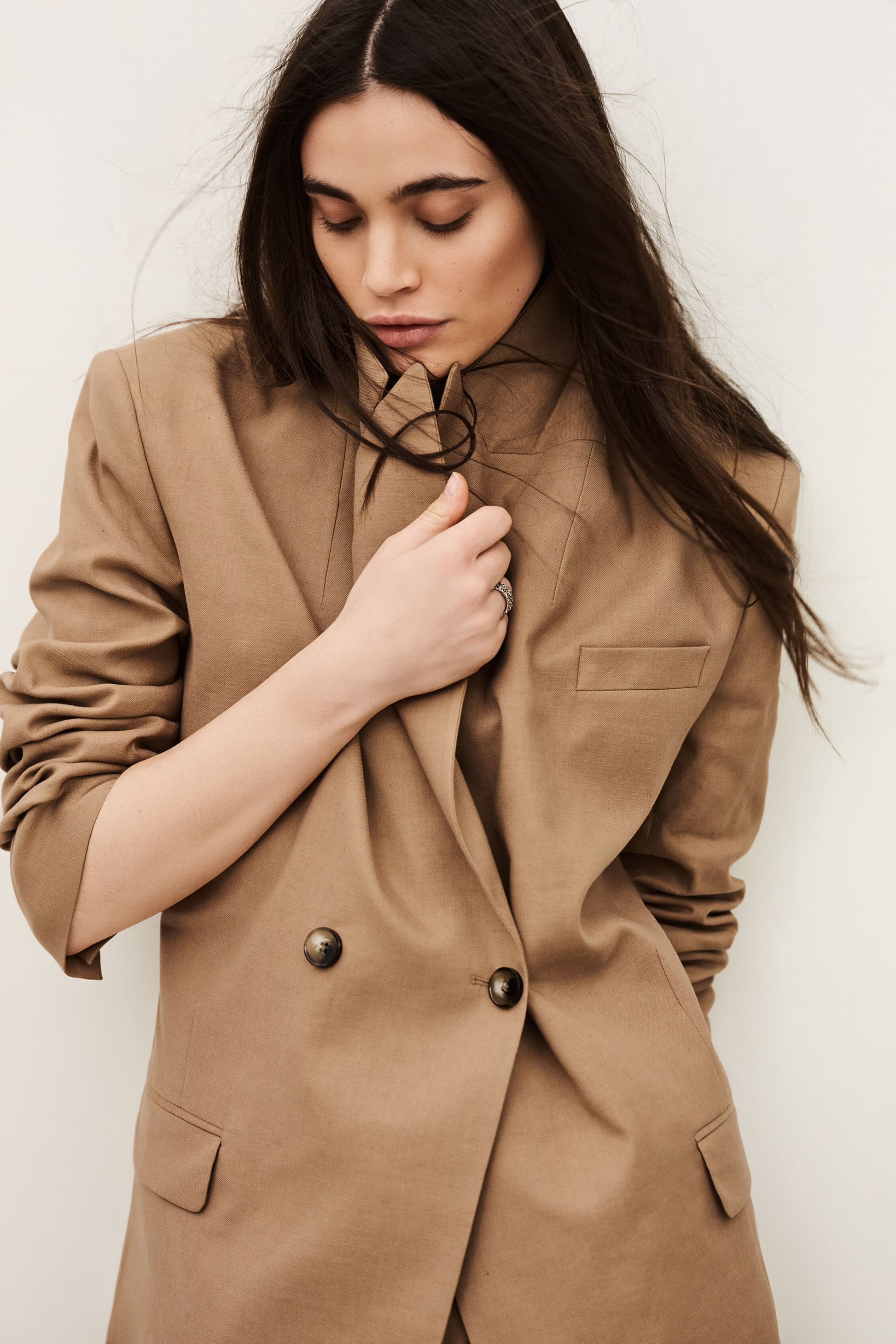 Woman wearing a brown blazer against a plain background