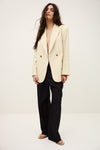 Woman wearing a cream blazer over a black top on a white background from ba&sh