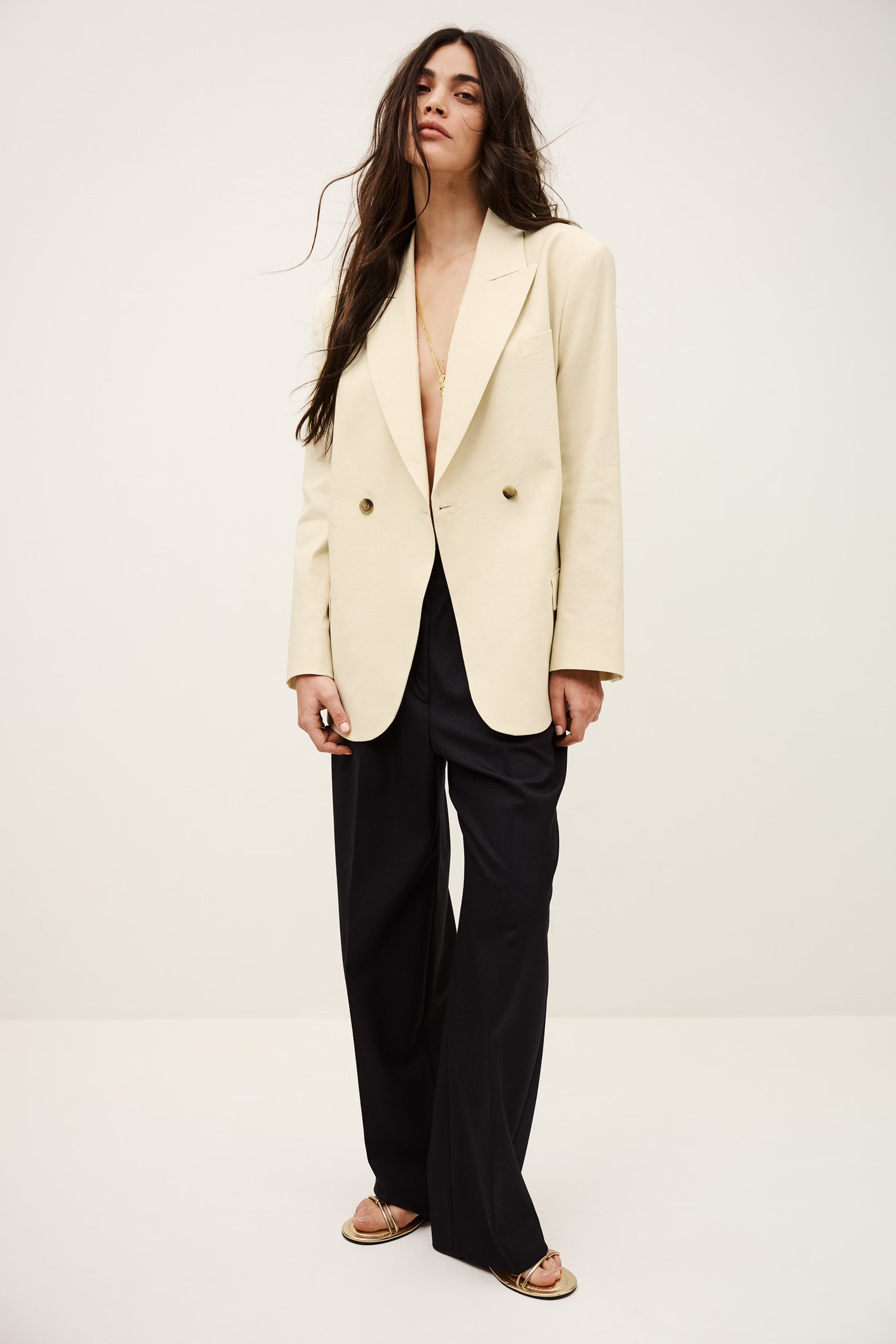Woman wearing a cream blazer over a black top on a white background from ba&sh