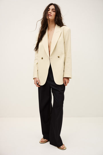 Woman wearing a cream blazer over a black top on a white background from ba&sh