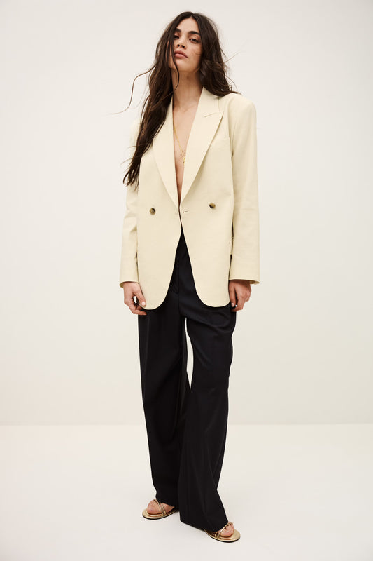 Woman wearing a cream blazer over a black top on a white background from ba&sh