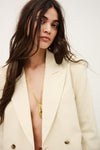 Woman wearing a cream blazer with a gold necklace against a white background from ba&sh