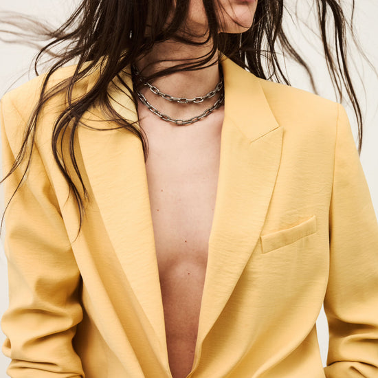 Person wearing a yellow suit with a plunging neckline against a neutral background from ba&sh