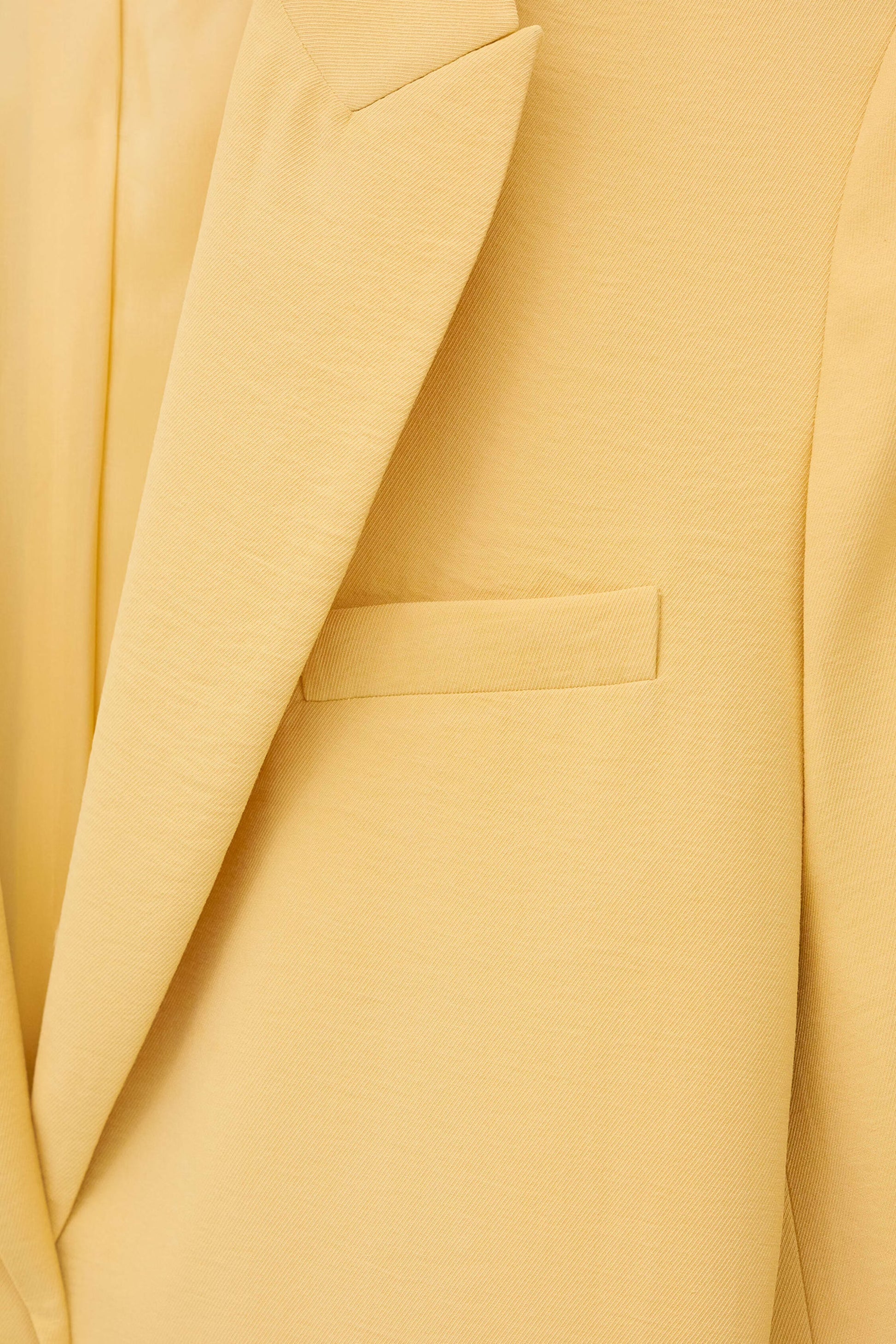 Close-up of a yellow suit jacket with a pocket and lapel from  ba&sh