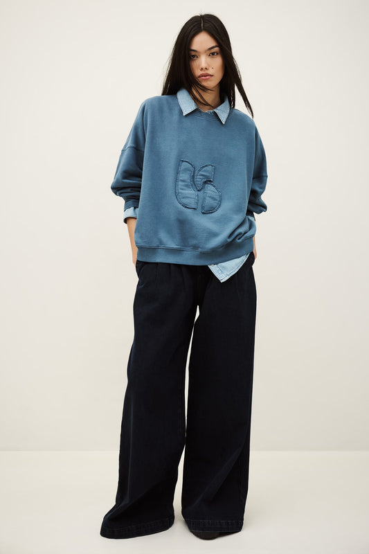 Person wearing a blue sweater and black pants on a white background