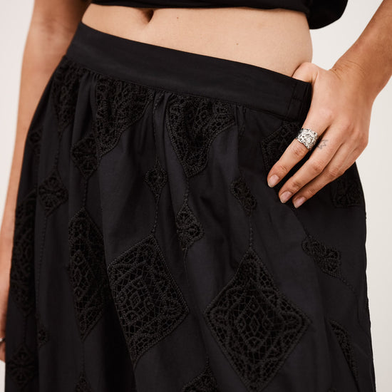 Close up detail of black cotton skirt with lace inserts