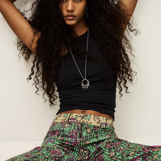 Woman wearing a black top and colorful pants against a white background