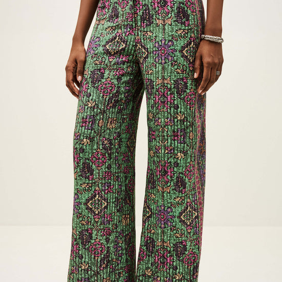 Person wearing green patterned pants on a white background