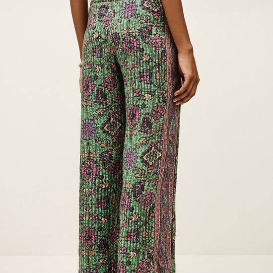 Green patterned pants worn by a person on a white background