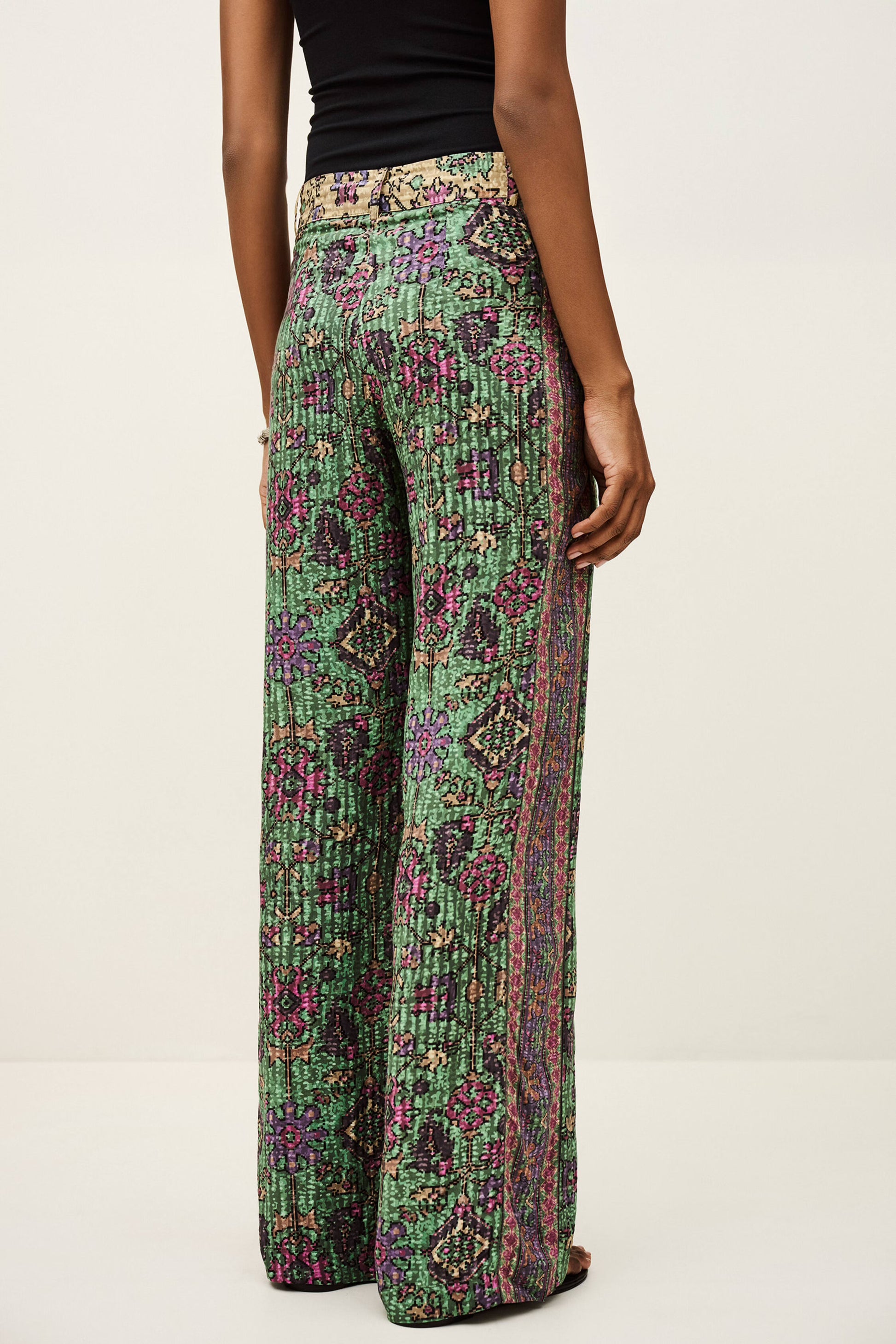 Green patterned pants worn by a person on a white background