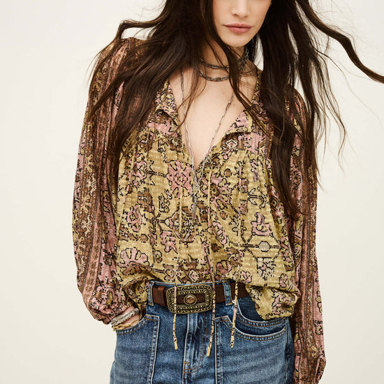 Woman wearing a floral blouse and denim shorts on a plain background