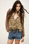 Woman wearing a floral blouse and denim shorts on a plain background