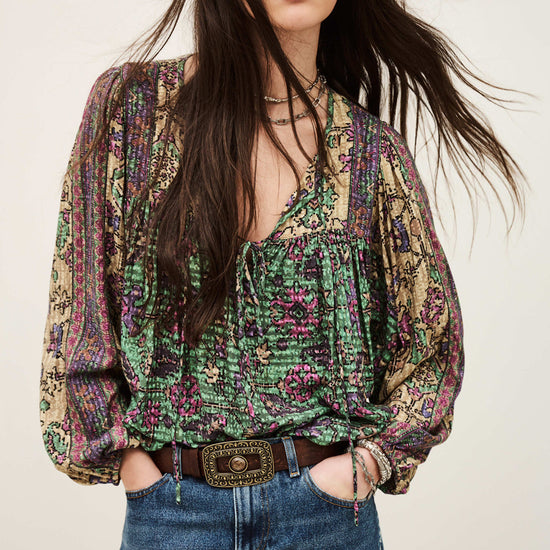 Woman wearing a patterned blouse and jeans against a plain background from ba&sh