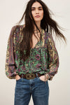 Woman wearing a patterned blouse and jeans against a plain background from ba&sh