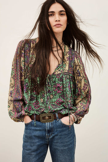 Woman wearing a patterned blouse and jeans against a plain background from ba&sh