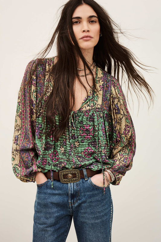Woman wearing a patterned blouse and jeans against a plain background from ba&sh