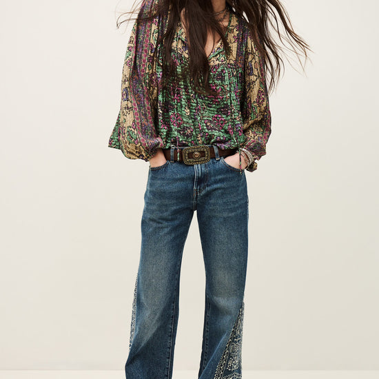 Woman wearing a patterned blouse and blue jeans on a white background from ba&sh