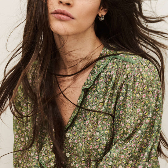 Woman wearing a green floral blouse with long hair against a neutral background from ba&sh