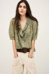 Woman wearing a green floral blouse with a plain background from ba&sh