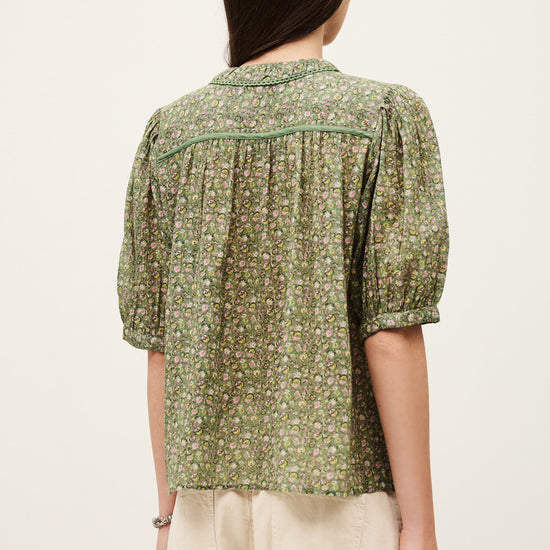 Woman wearing a green floral blouse with puffed sleeves on a white background from ba&sh
