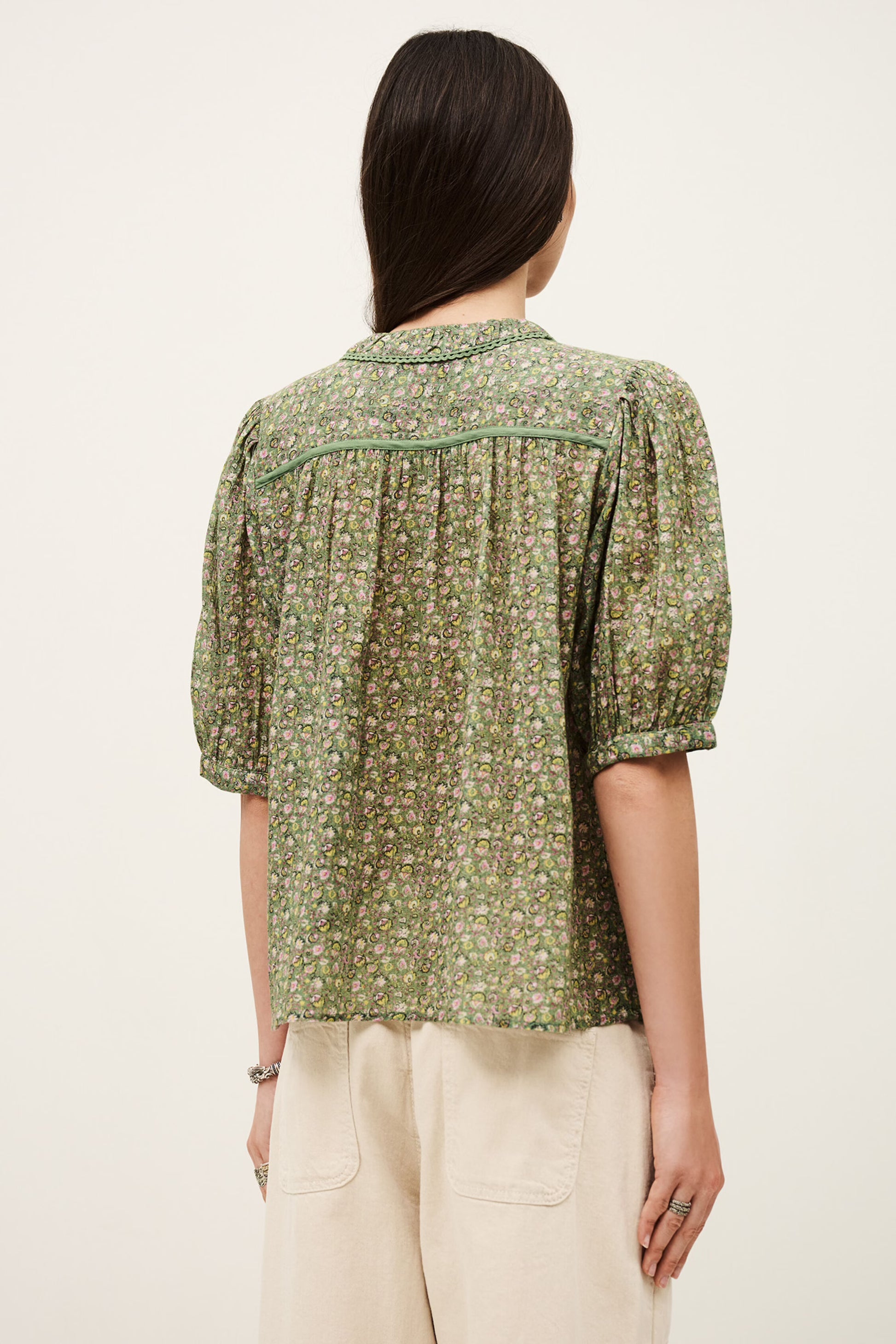 Woman wearing a green floral blouse with puffed sleeves on a white background from ba&sh
