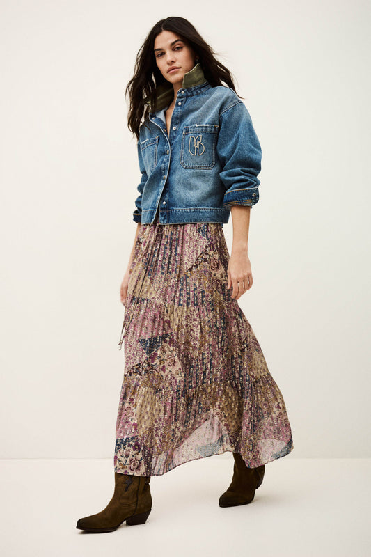 Woman wearing a denim jacket and patterned skirt on a white background